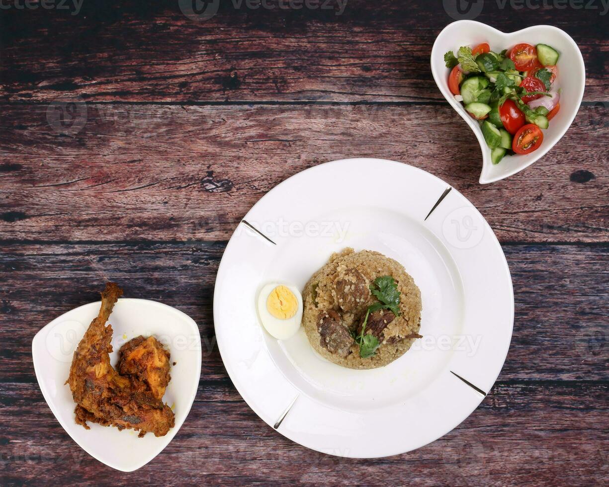 carne de vaca Biryani tehari con hervido huevo cilantro hoja adornar en blanco plato pollo curry maceta asado pierna triángulo plato tomate Pepino cebolla chile cilantro ensalada ciervo forma plato conjunto foto