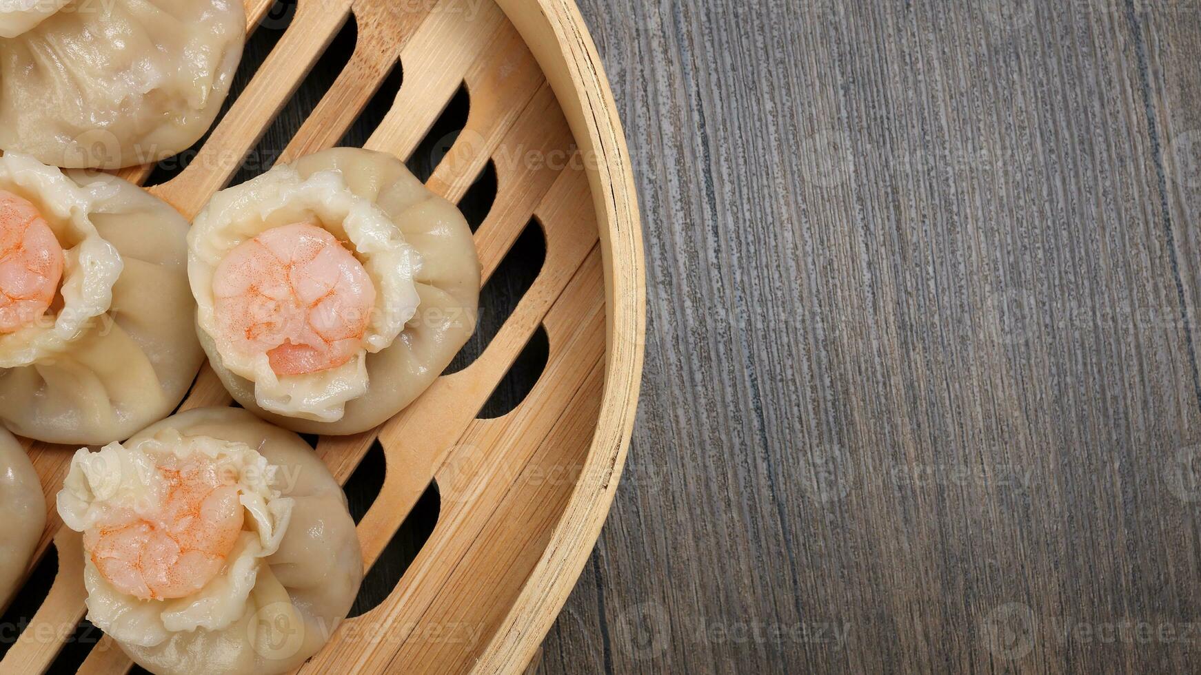 Prawn shrimp shaomai dim sum dumpling in bamboo steamer on rustic wood background photo
