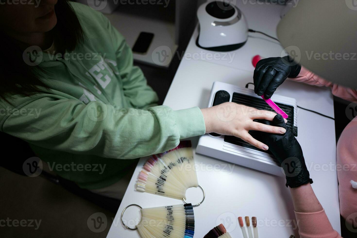 Manicure master working with female client in beauty salon. Manicurist makes woman nail. photo