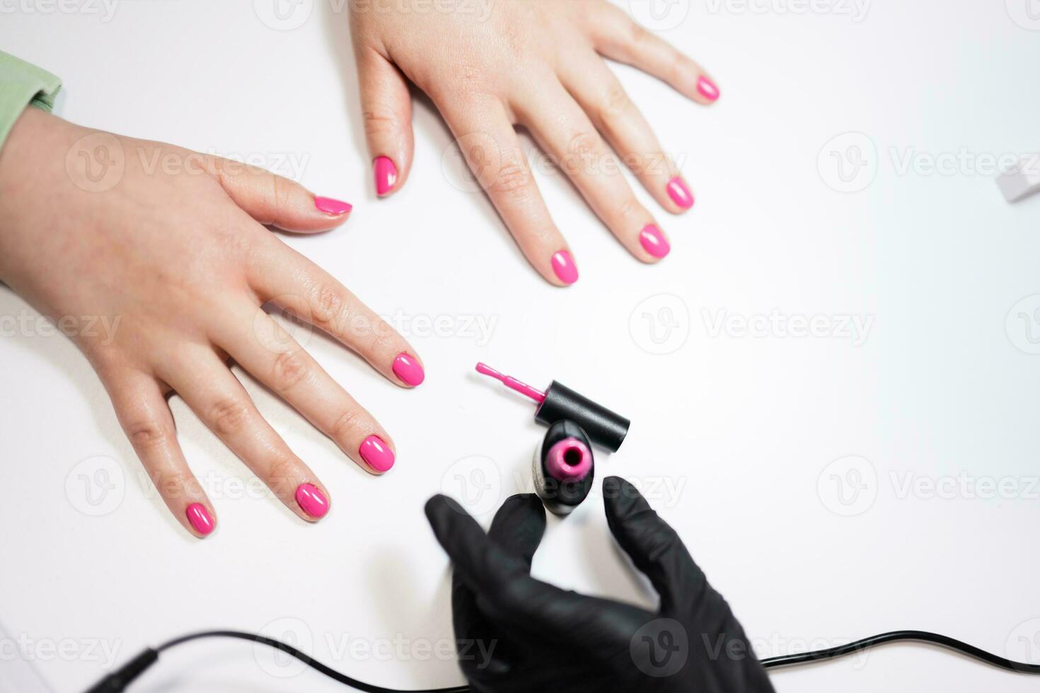 Close up hands of manicure master working with female client in beauty salon. Manicurist makes woman nails. photo