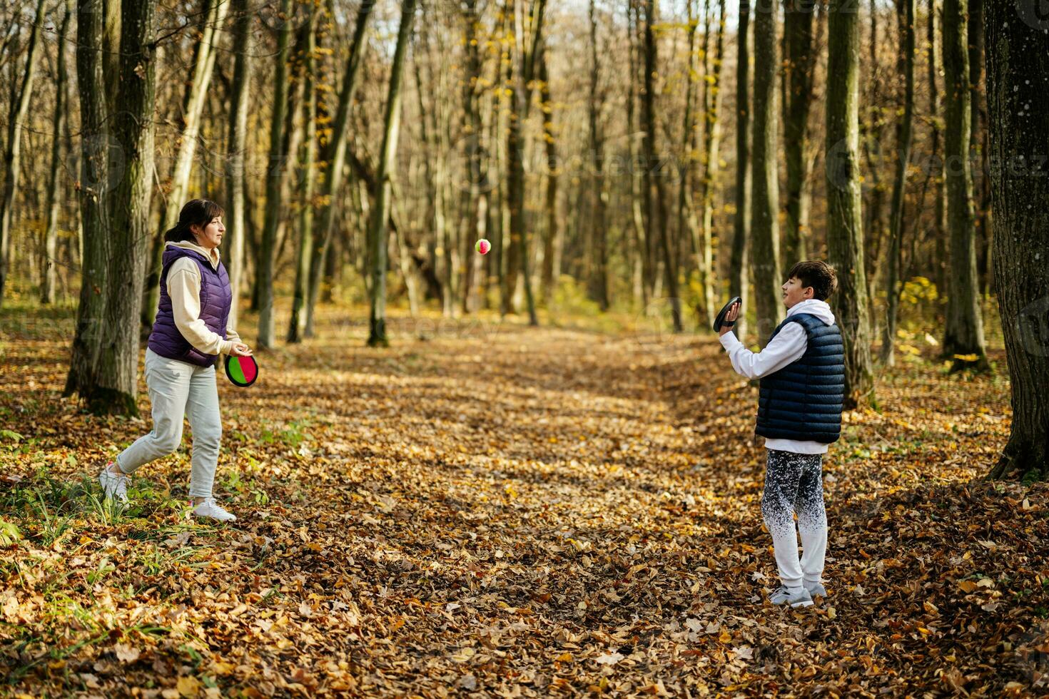 madre con hijo jugar en el bosque de otoño atrapar y lanzar el juego de pelota. foto