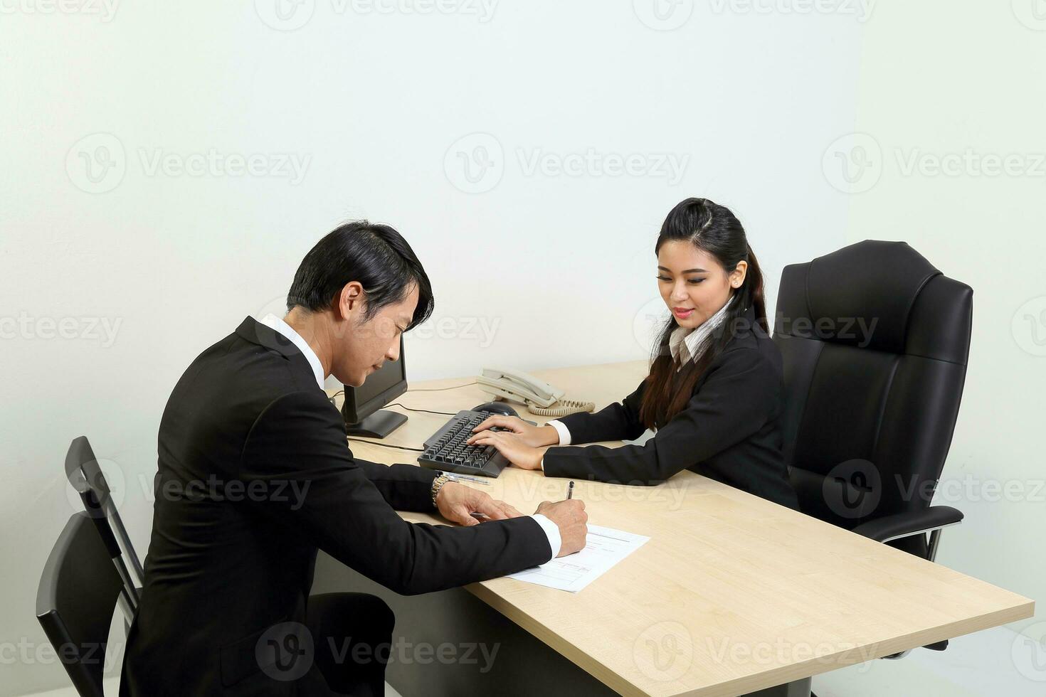 joven asiático masculino hembra vistiendo traje sentado a oficina escritorio pensando reunión discutiendo firmar documento acuerdo foto