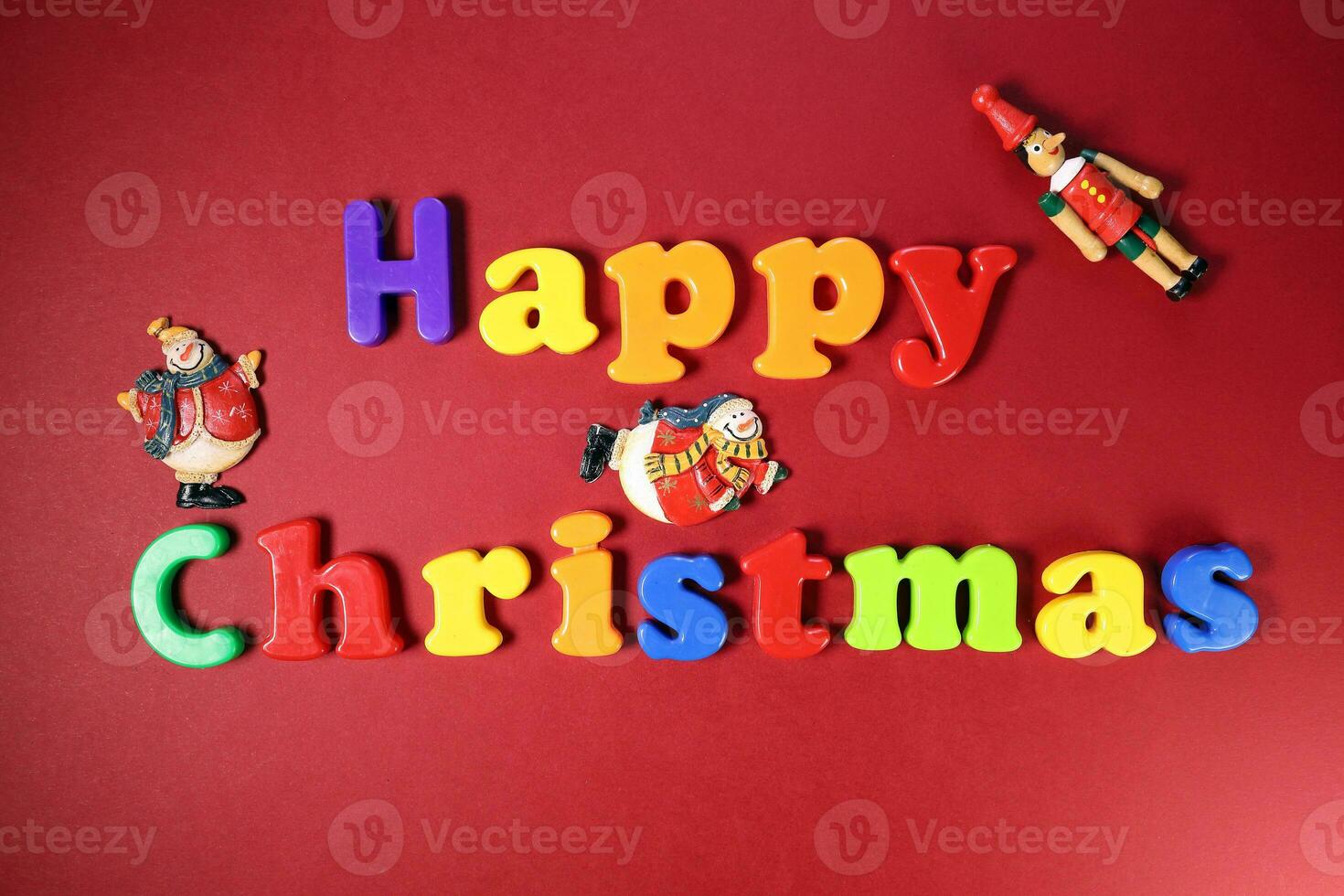 Happy Christmas sign on red paper background color plastic alphabet Santa clause nutcracker soldier ornament photo