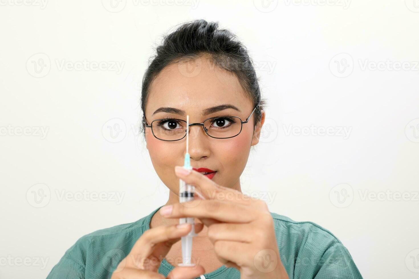 Young asian malay female doctor holding injection syringe needle look at needle on white background photo