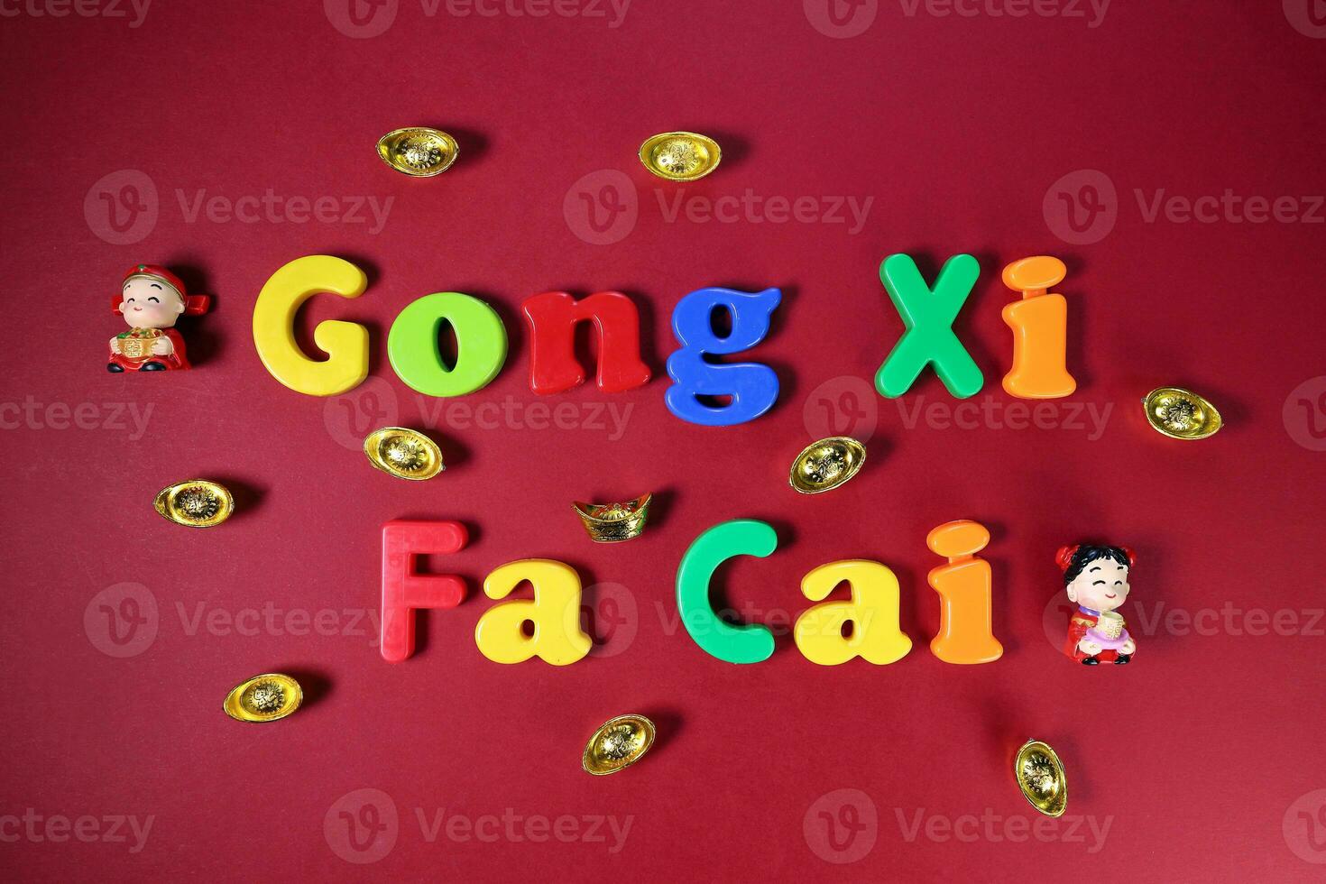 Plastic alphabet sign lettering Gong Xi Fa Cai Chinese New Year on maroon red paper background ornaments ingots photo