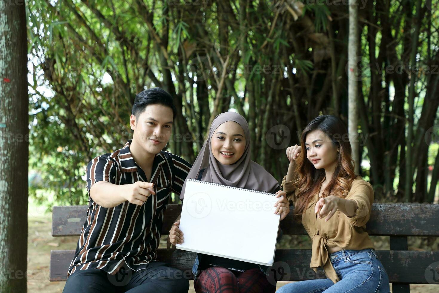 Young Asian Malay man woman outdoor green park walk talk discuss mingle photo