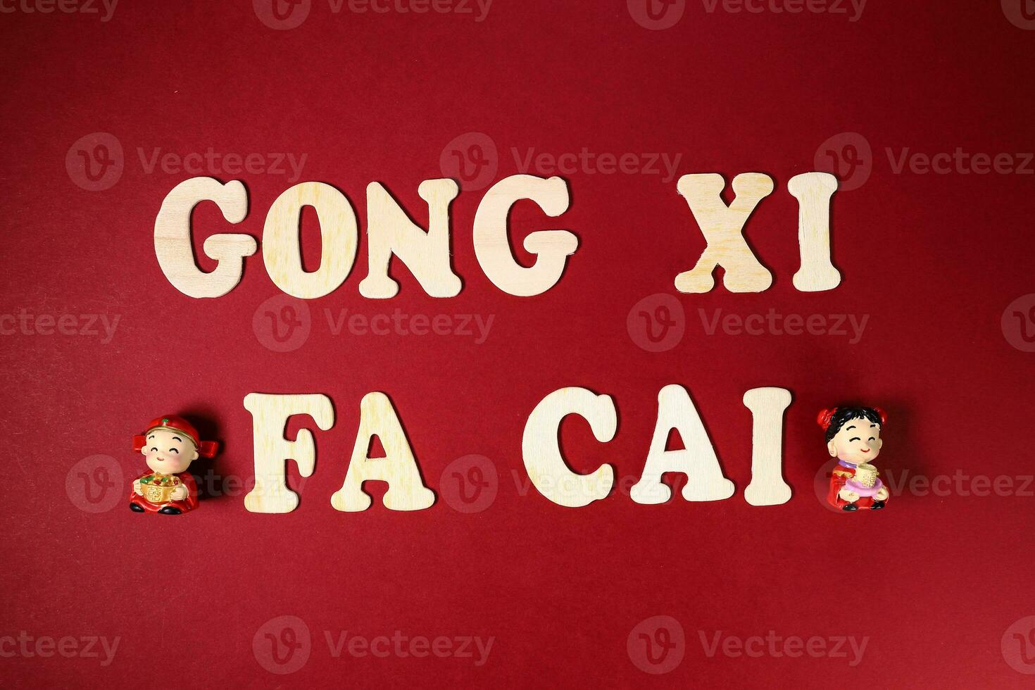 Wooden alphabet sign lettering Gong Xi Fa Cai Chinese New Year on maroon red paper background figurine photo