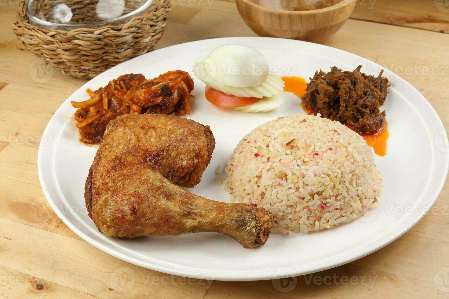 Indonesian royal dish nasi bojari with deep spiced deep fried chicken leg sambal prawn curry beef rendang boild egg cucumber and tomato slice photo