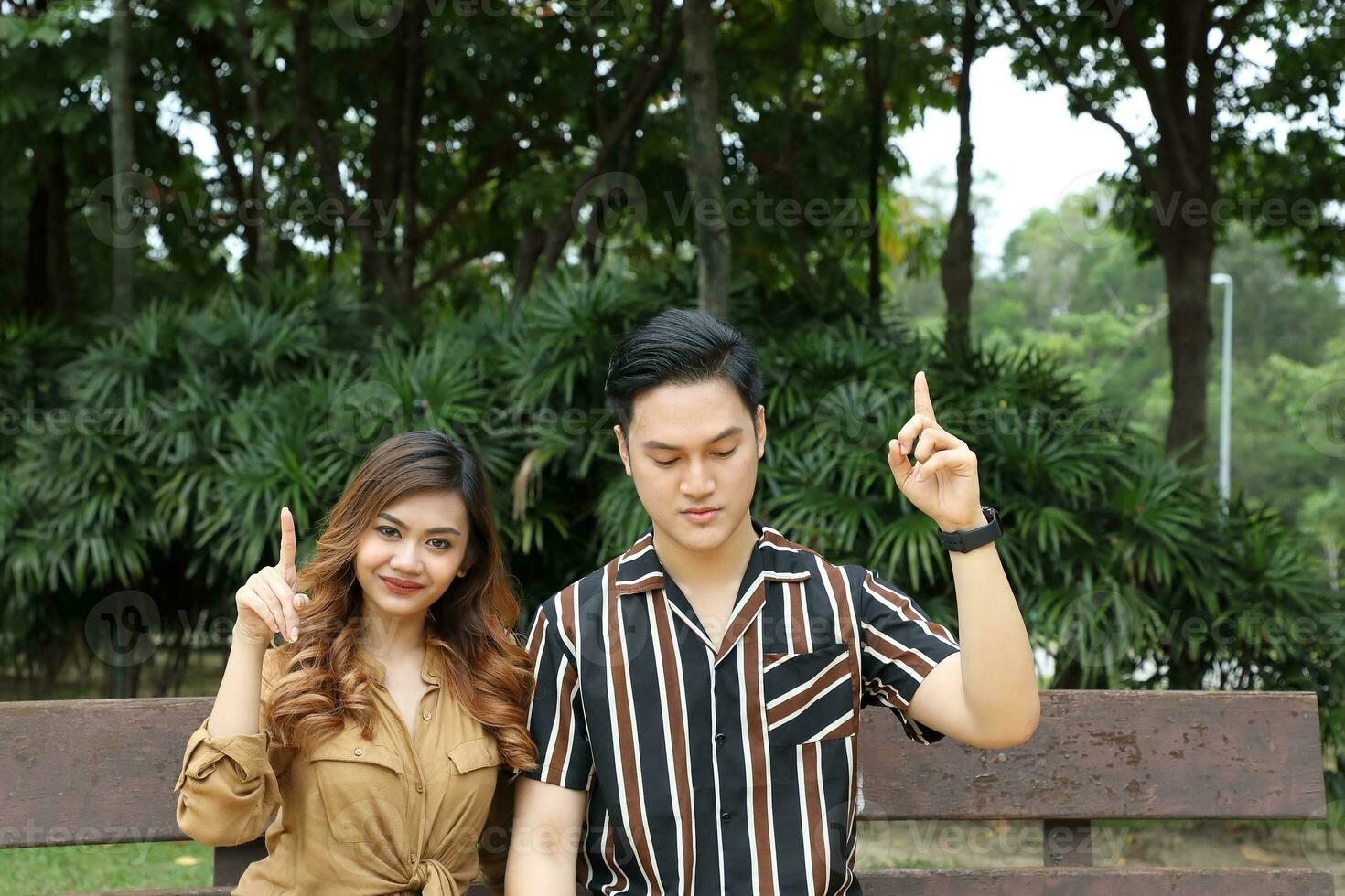 Young Asian Malay man woman outdoor green park walk talk discuss mingle under umbrella photo