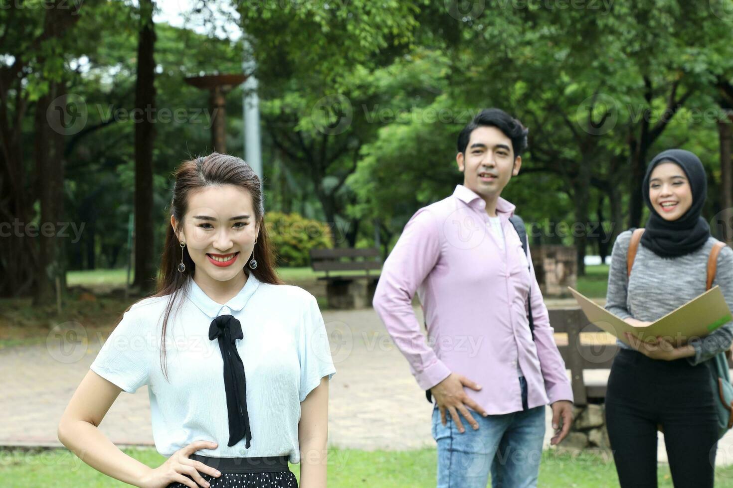 Young asian malay chinese man woman outdoor park walk stand study talk discuss point laptop file book backpack female look forward male look point photo