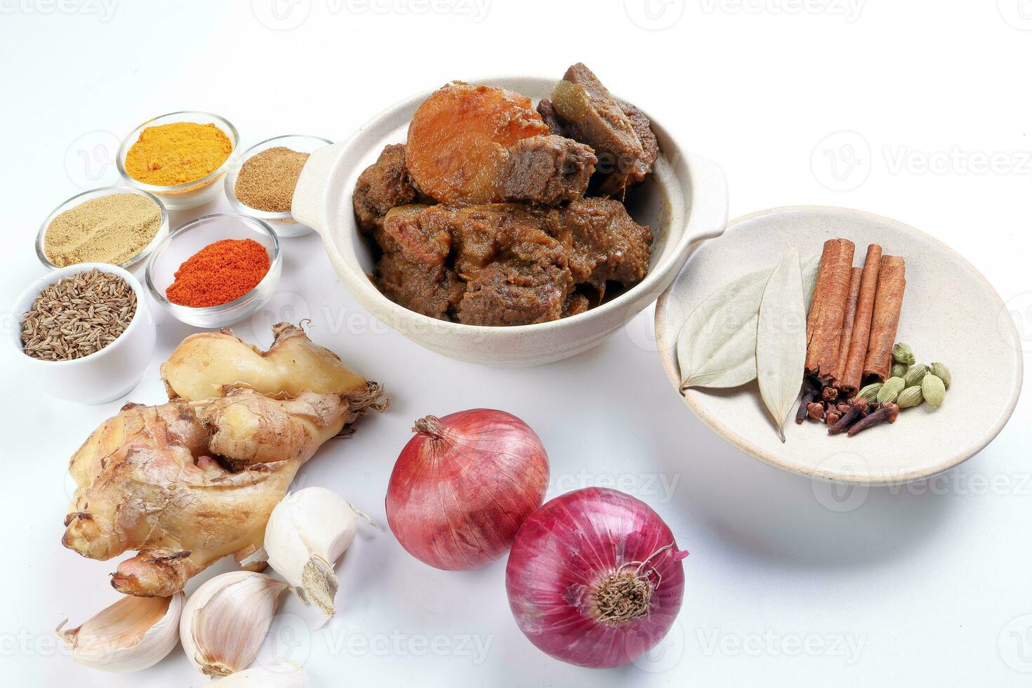 Beef bhuna dry curry with potato in ceramic bowl ingredients chilli cumin coriander turmeric powered salt onion garlic ginger bay leaf cinnamon cardamom clove over white background photo