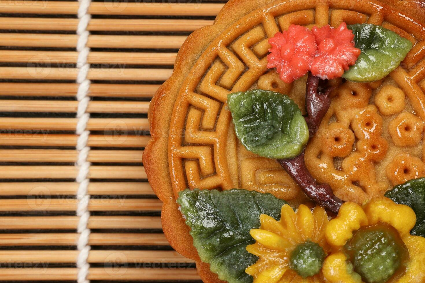 Colorful flower decorated mooncake Chinese mid autumn festival on bamboo food mat background photo
