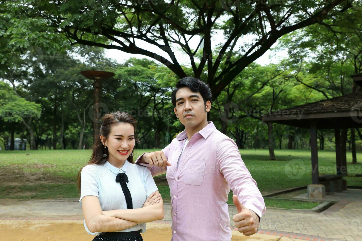 young asian malay chinese man woman outdoor park walk stand study talk discuss laptop file book backpack pose look forward thumbs up photo