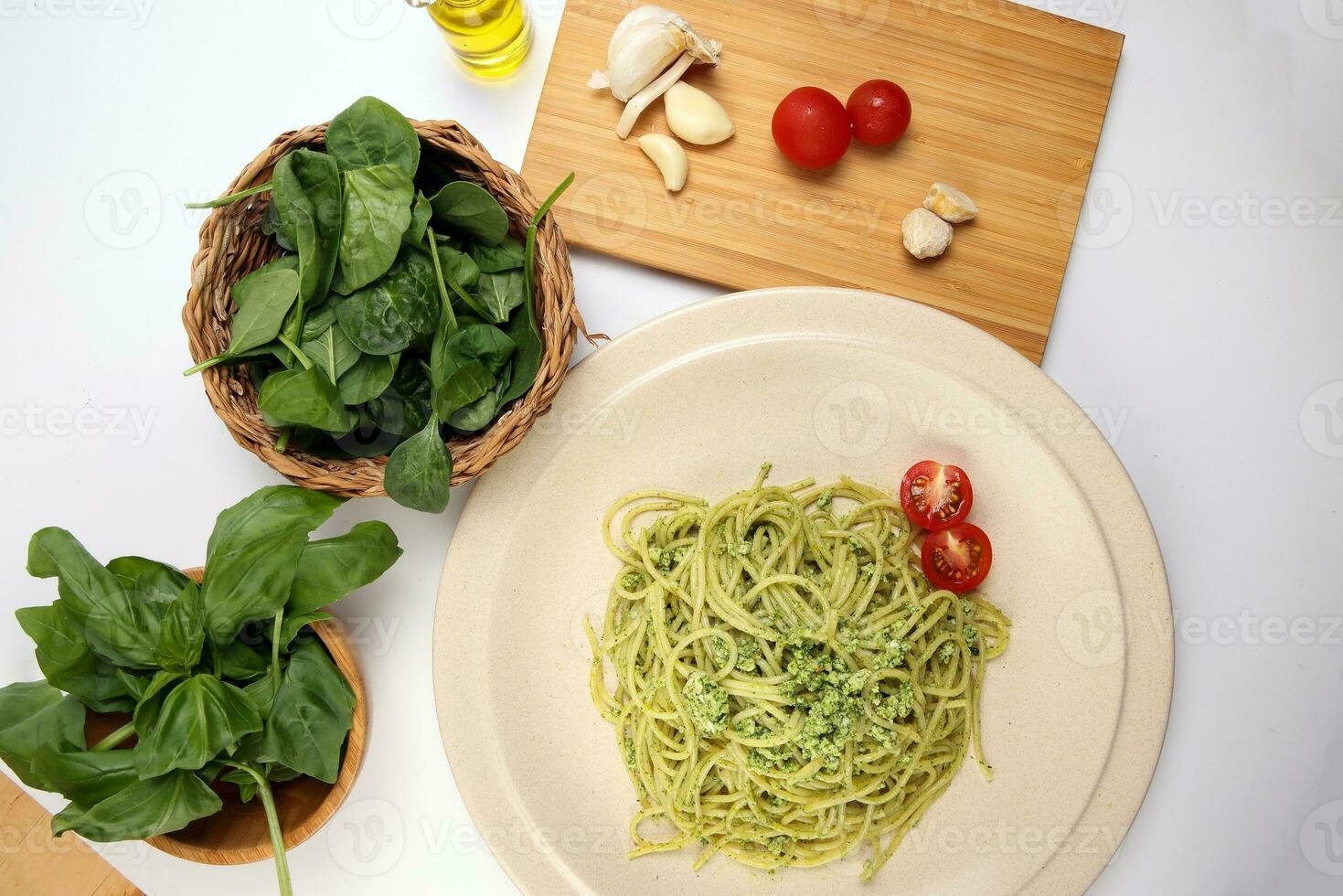 Asian style spaghetti with minced chicken spinach thai basil tomato garlic nutmeg olive oil presto sauce served on badge ceramic plate over on white background ingredients wooden board bowl photo