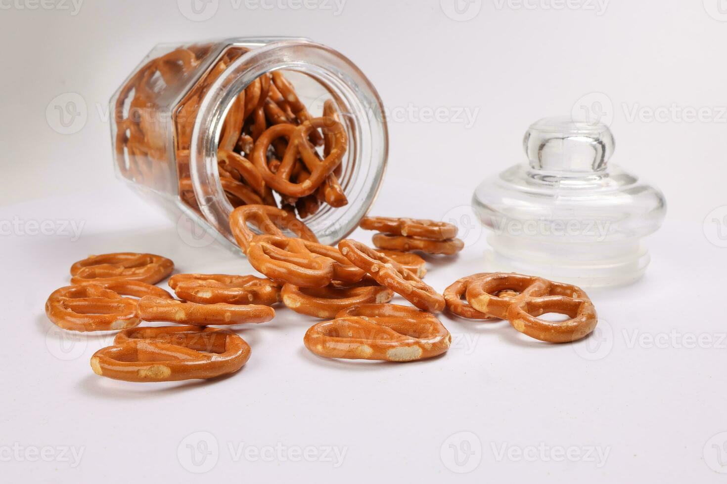 Pretzel cracker in a glass jar pouring dropping on white background photo