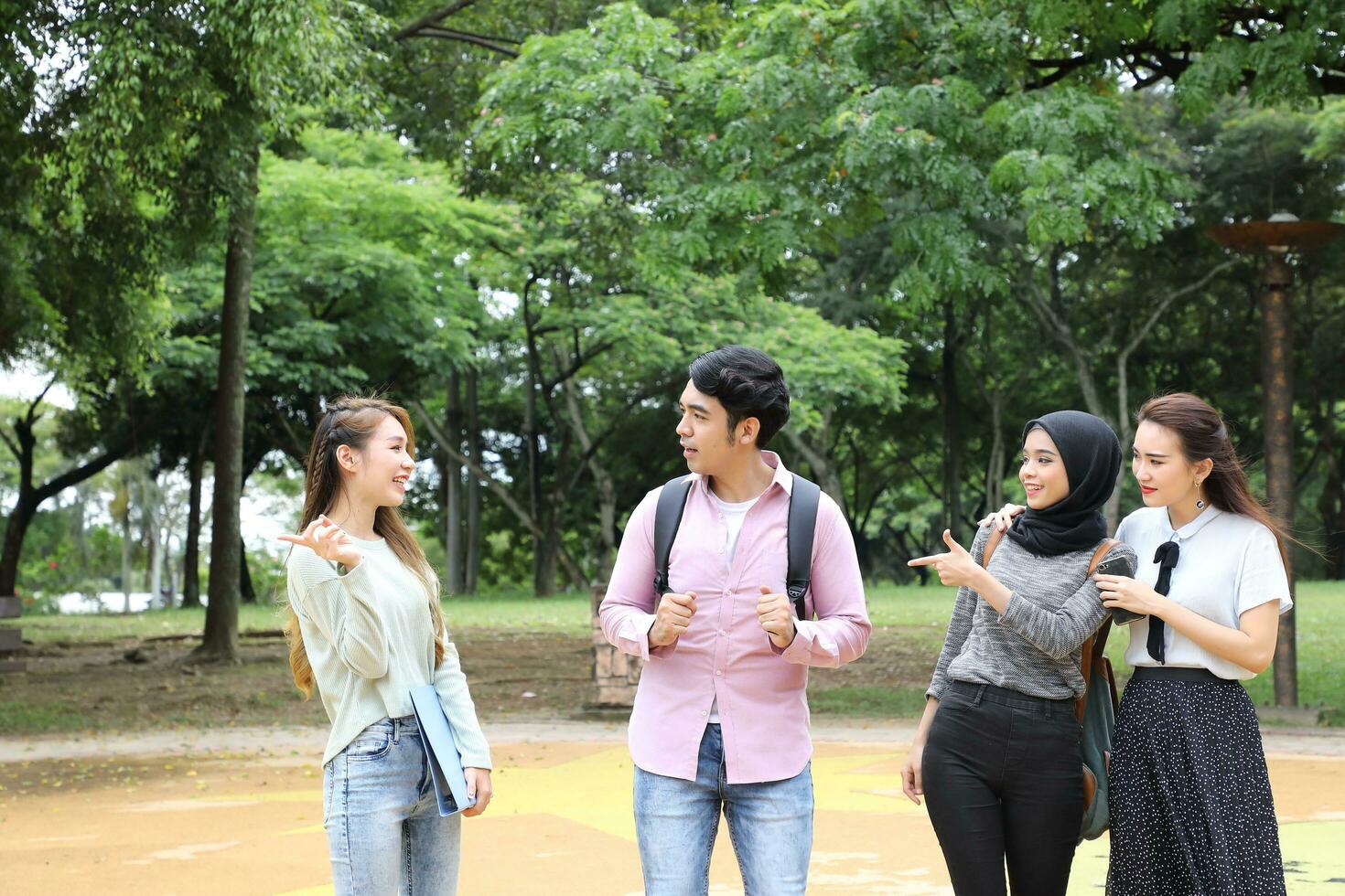 Young asian malay chinese man woman outdoor park walk stand study talk discuss point laptop file book backpack photo