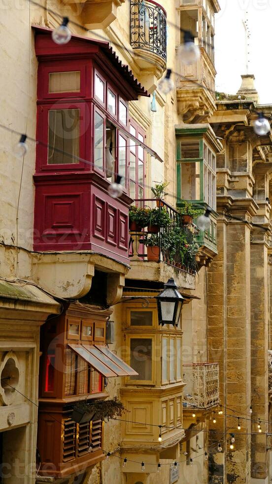 Exterior of typical houses on the Mediterranean island of Malta. Typical residential houses in the cities in Malta, multiple floors and colorful wooden balconies and beautiful limestone buildings. photo