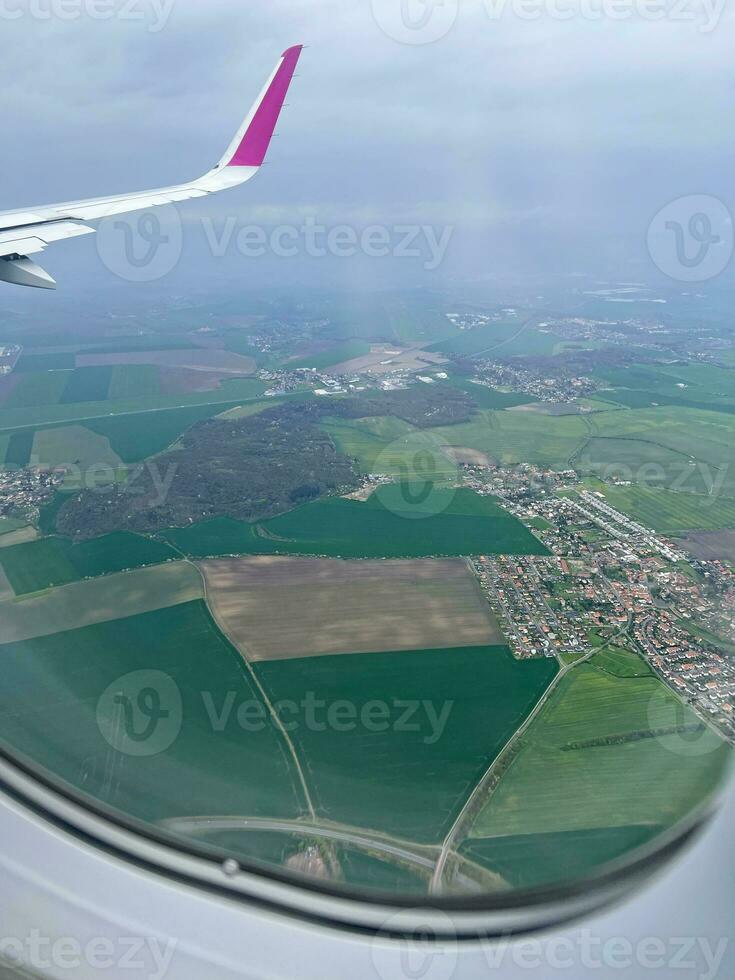 View from the airplane window. Beautiful view of green agricultural field and village. Wonderful panorama seen through window of an plane. Traveling by air concept photo