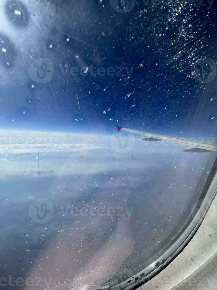 View from the airplane window. Beautiful cloudscape with blue sky. Wonderful panorama above white clouds as seen through window of an plane. Traveling by air concept. Selective focus. photo