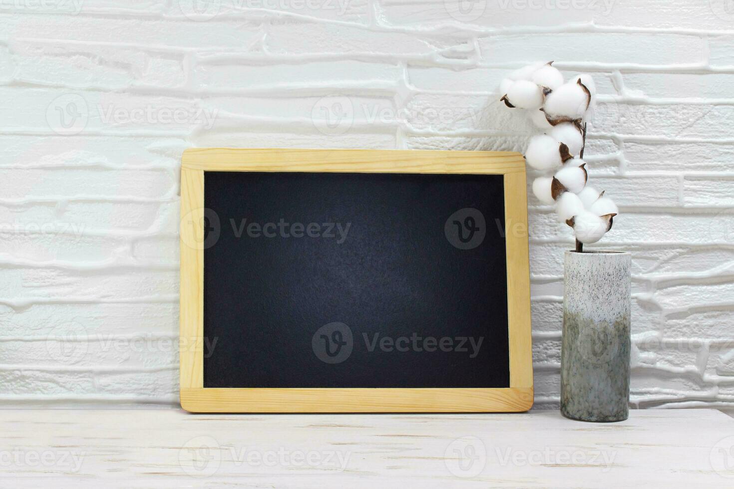 Black board for text, mock up next to vase with cotton on table. Front view empty. Minimal concept. Copy space photo