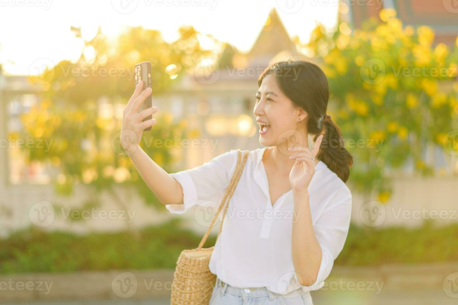 Portrait young beautiful asian woman using smartphone to video call with friend and explore street on summer vacation in Bangkok, Thailand photo