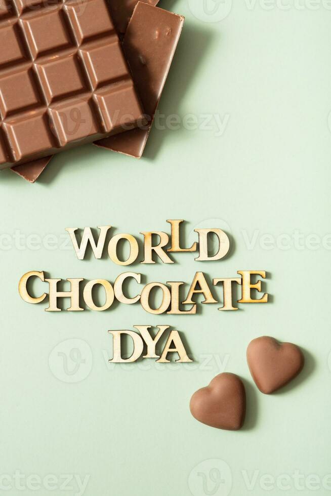 World chocolate day text with chocolate flat lay, top view on pastel green background photo