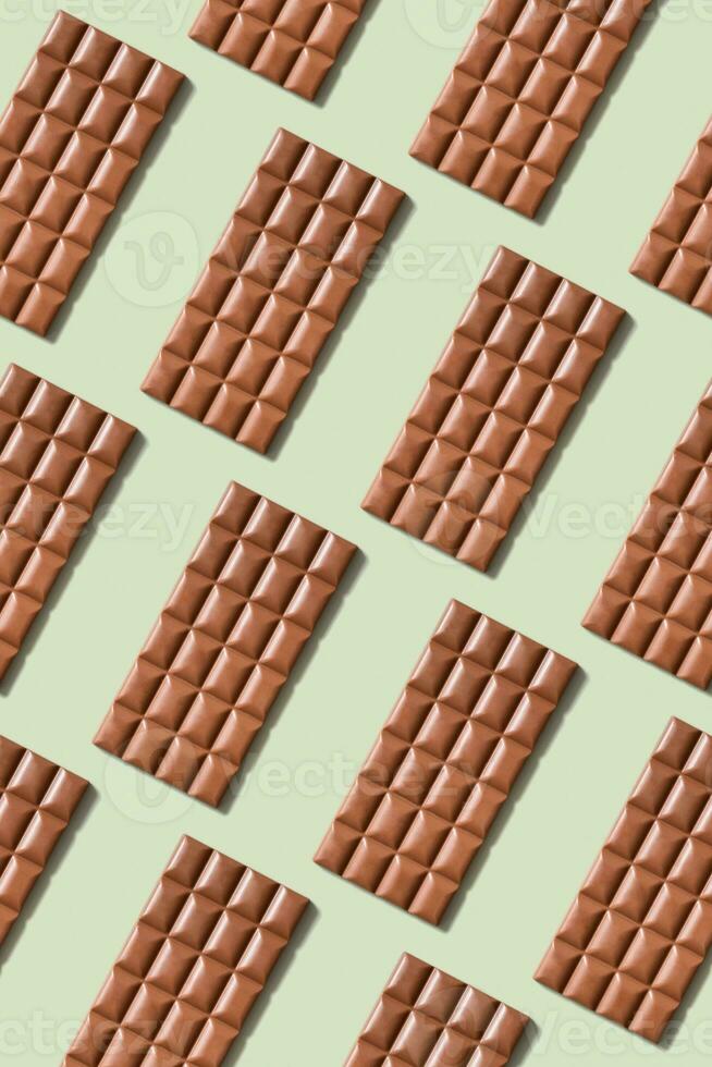 Chocolate bar pattern flat lay, top view on pastel green background photo