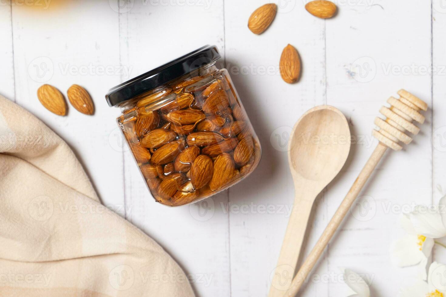 Glass jar with honey and nuts on beige background. Almond in honey. Top view photo