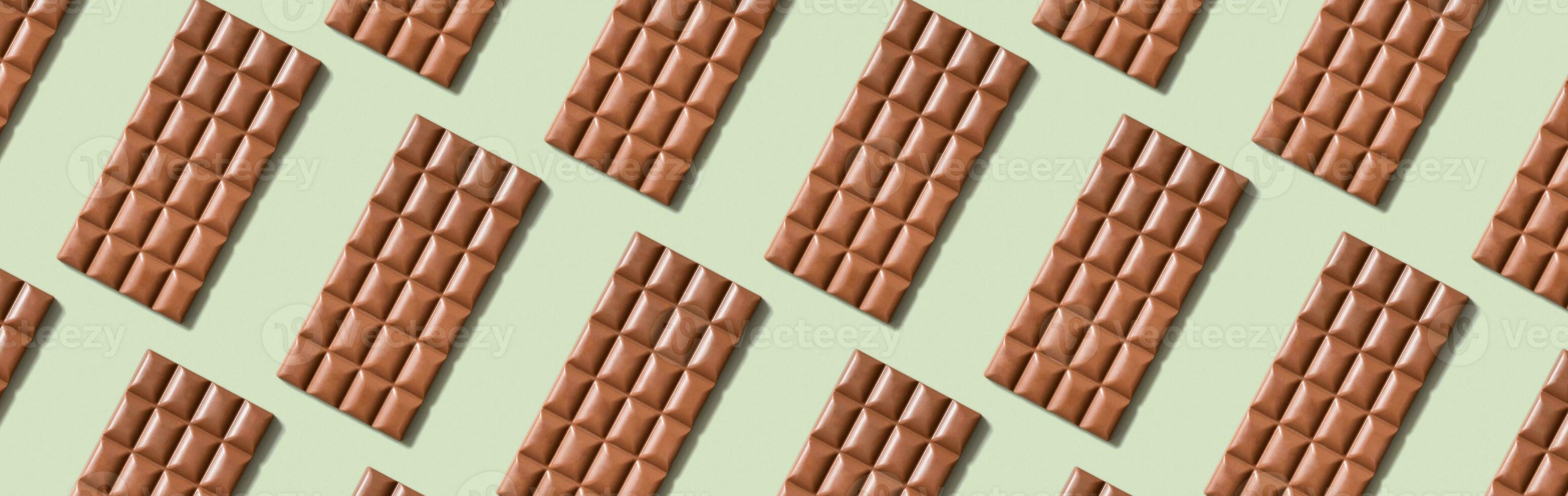 Chocolate bar pattern flat lay, top view on pastel green background photo