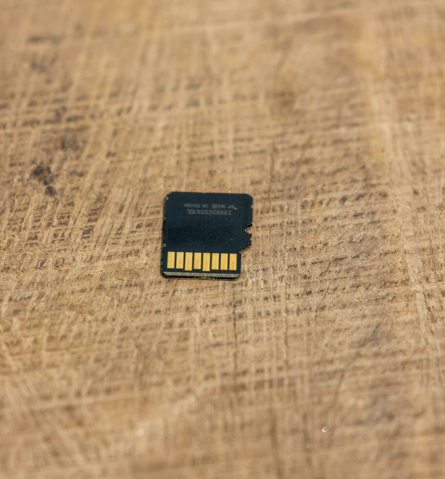 Detailed micro SD card on a wooden table. Micro SD card back side close up shot on a wooden surface. Memory card close up shot on a wooden surface. Action camera accessories and memory card. photo