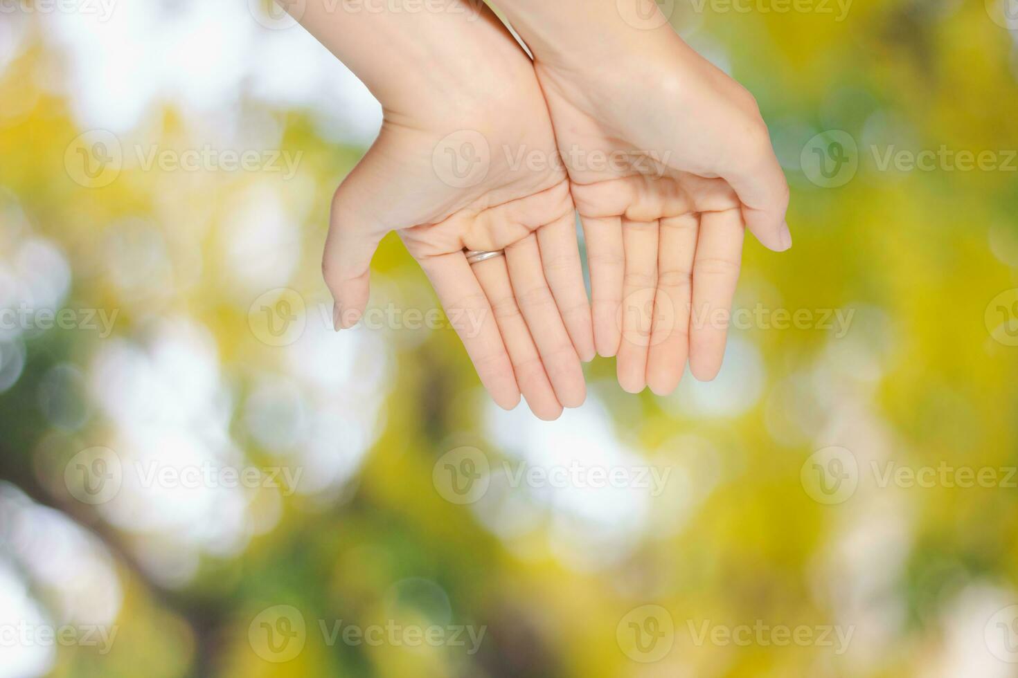 Closeup of woman open two empty hands with palms up from the top for pray to God and blessing on green blur background photo