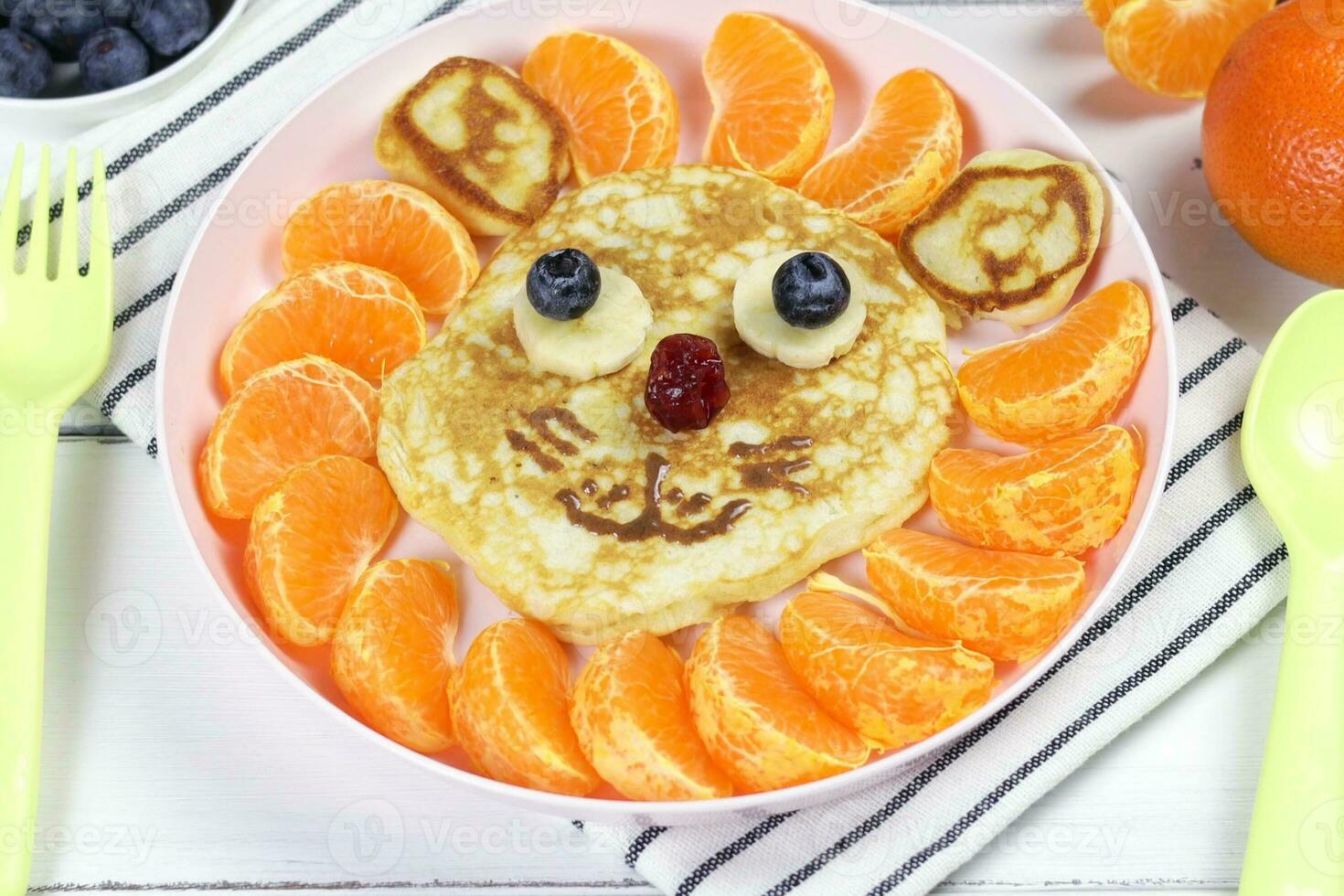 Pancakes in the shape of a funny lion with mandarin slices. A creative idea for a fun kids dessert or breakfast photo