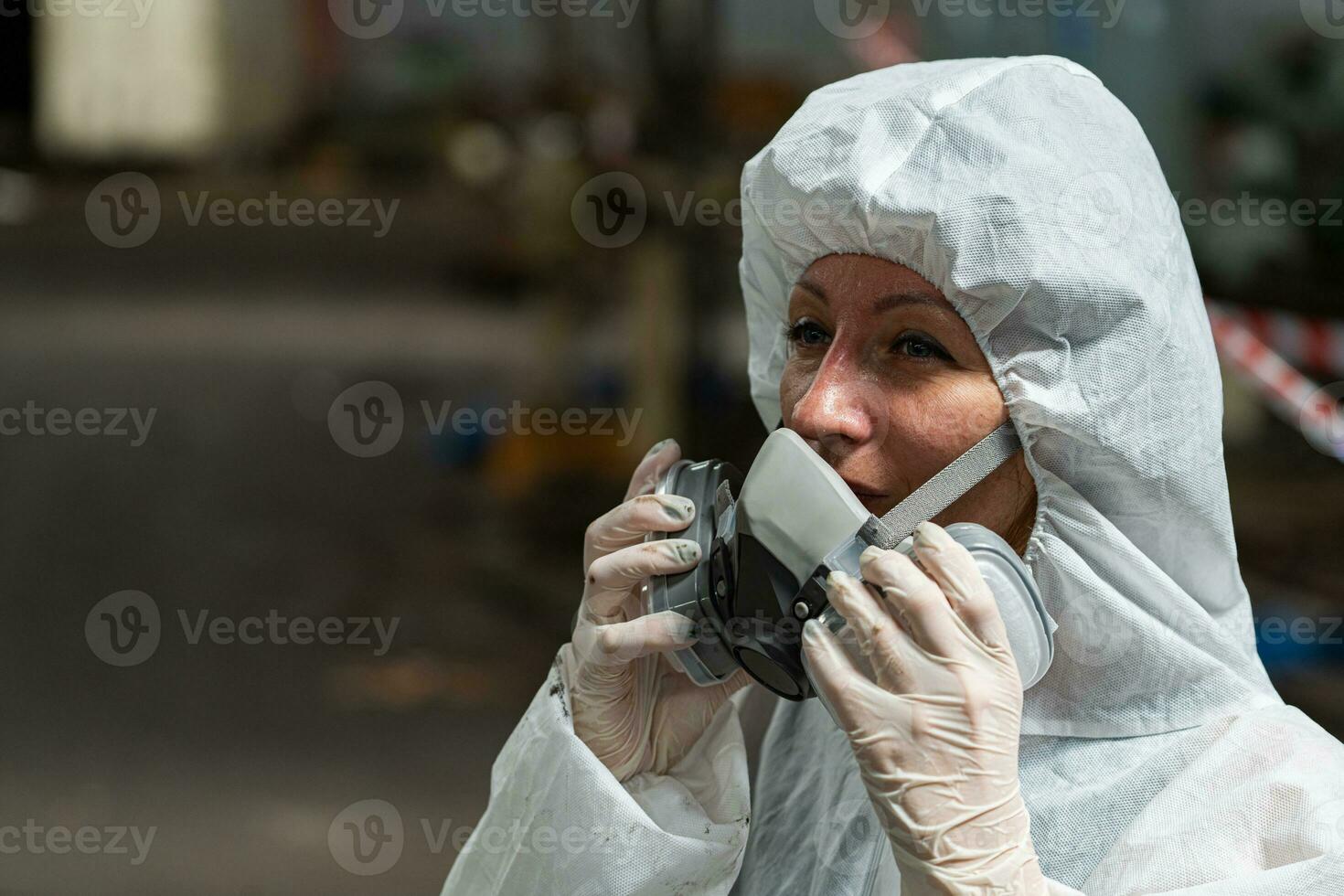 Caucasian woman workers wearing PPE protective clothing and gas masks, goggles, holding old petrol tanks. photo