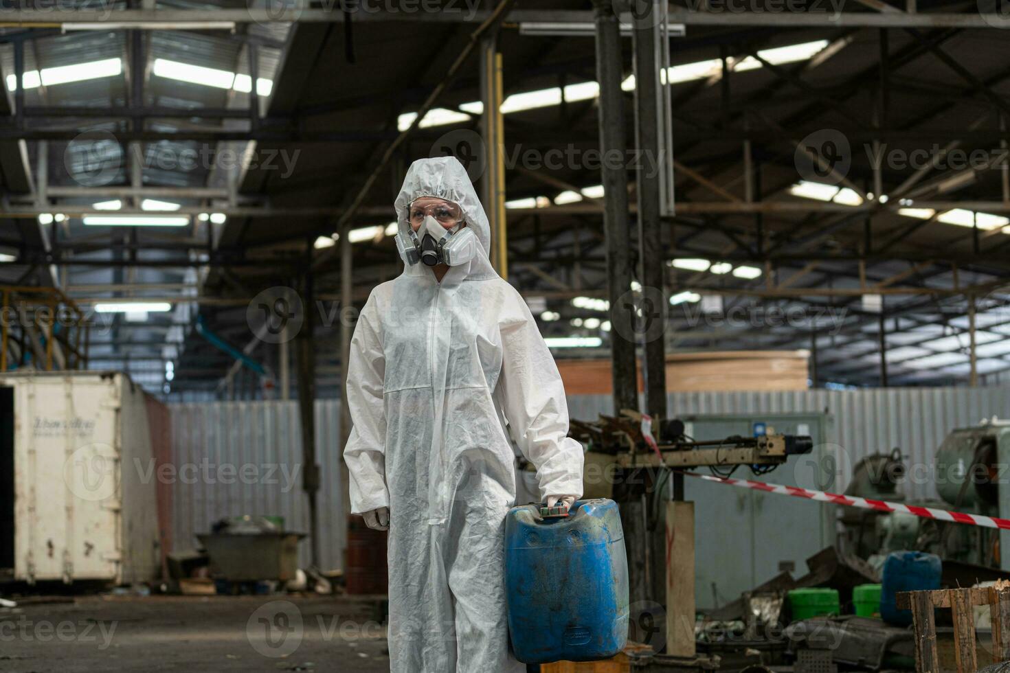 Caucasian woman workers wearing PPE protective clothing and gas masks, goggles, holding old petrol tanks. photo