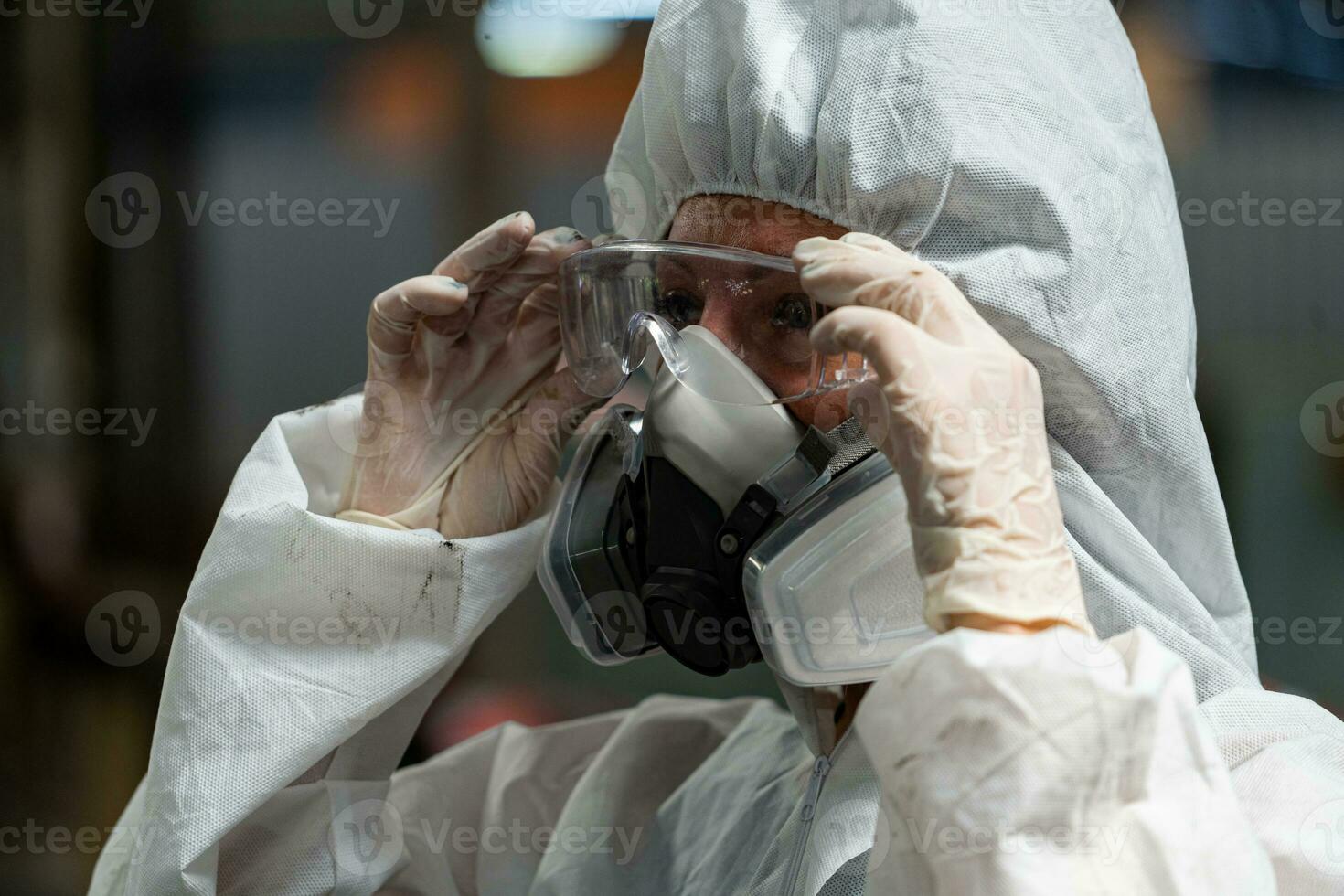 Caucasian woman workers wearing PPE protective clothing and gas masks, goggles, holding old petrol tanks. photo