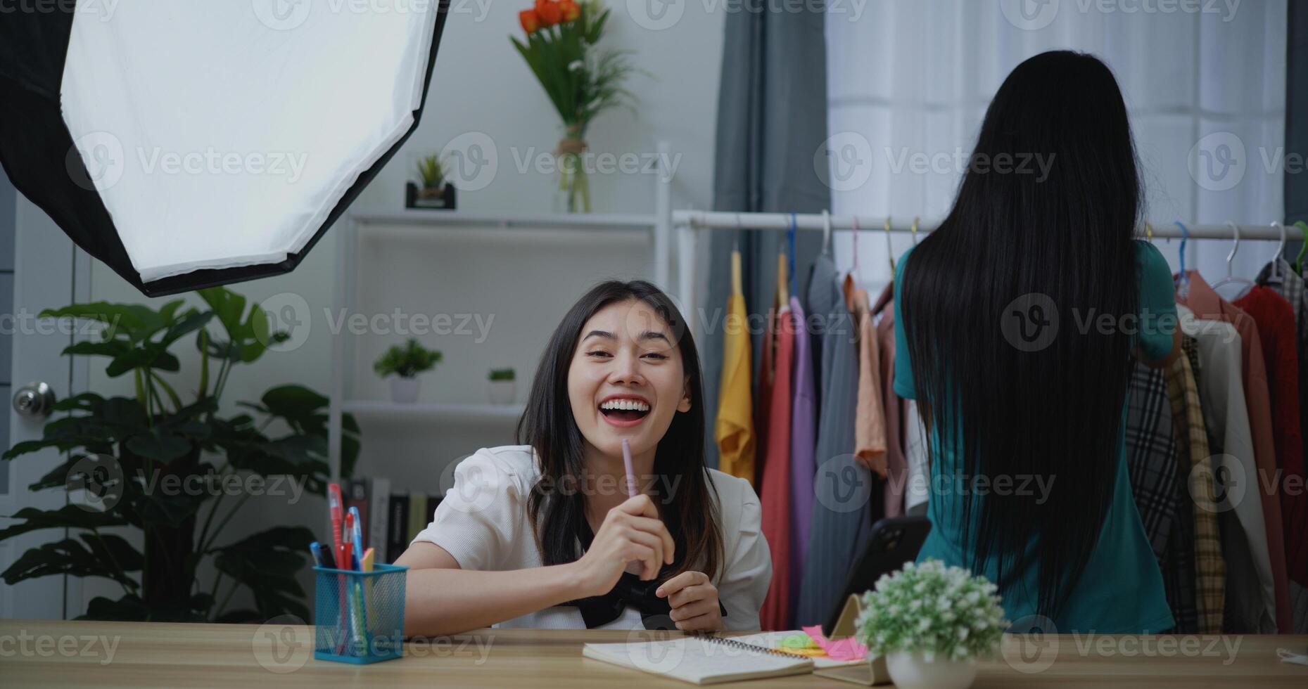Young Beautiful Asian woman live streaming at clothes shop photo