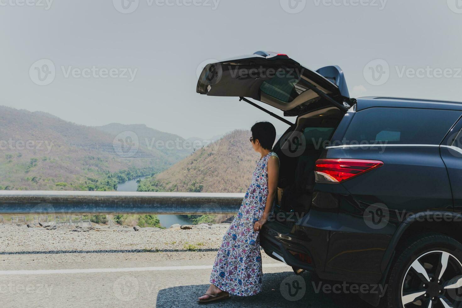 Relaxed tourist woman leaning again car wiht open trunk. photo