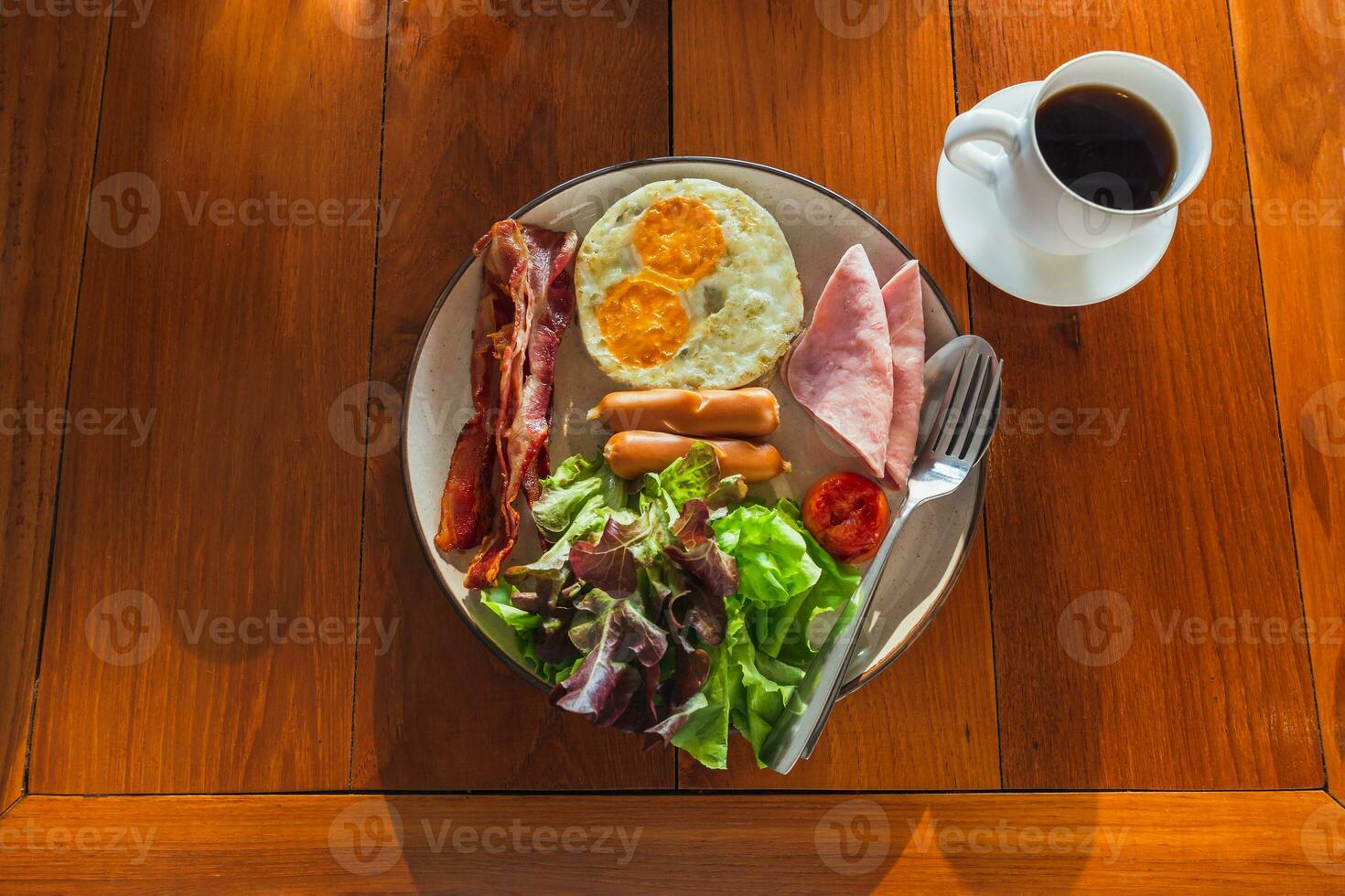Healthy breakfast meal of ham, fried eggs and crispy bacon with vegetable salad. photo