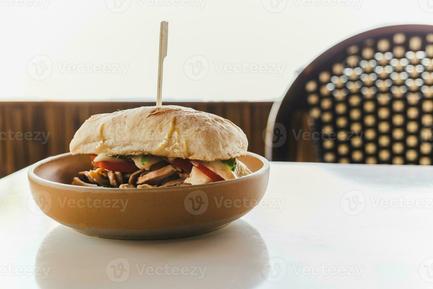 Chicken and cheese panini sandwich with fresh tomato on table. photo