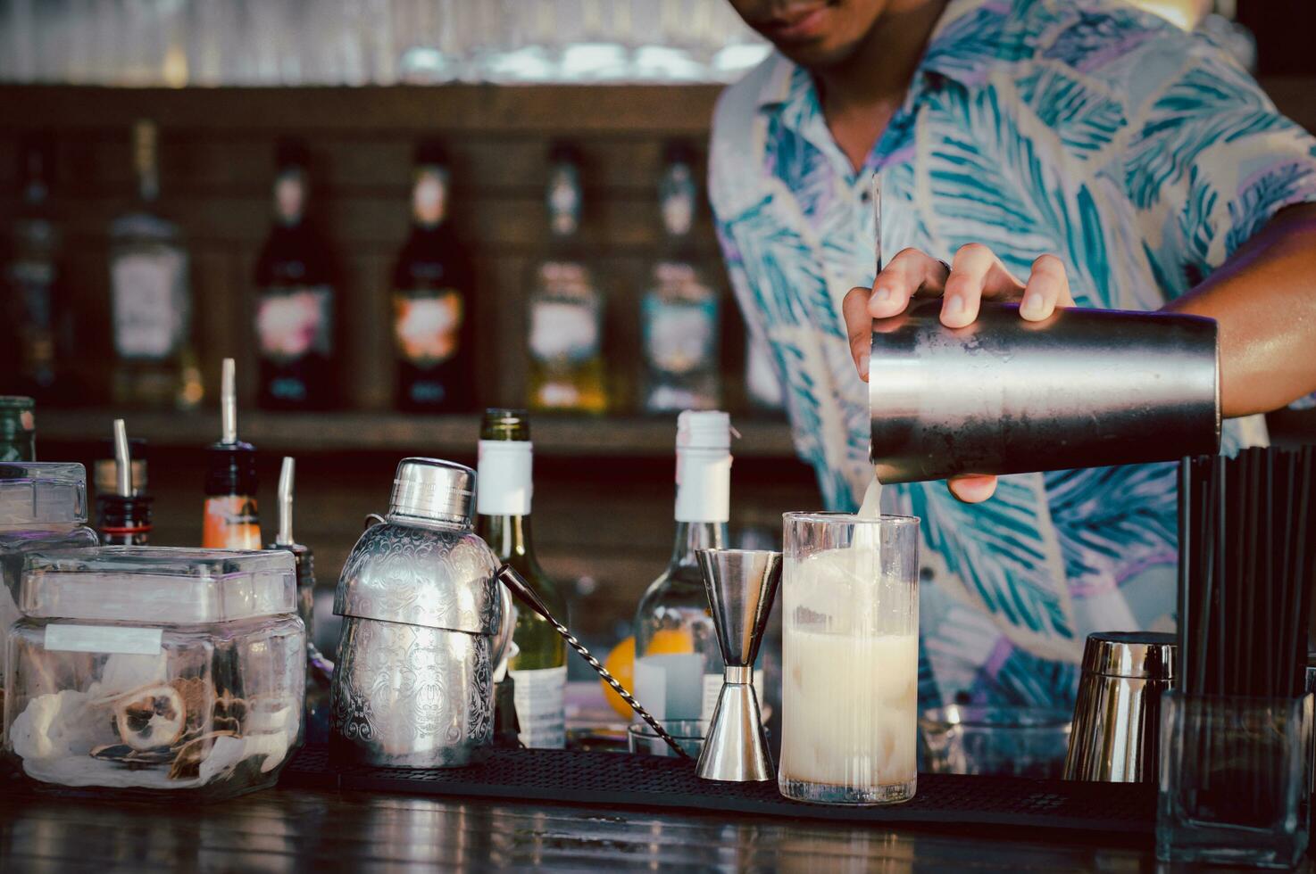 barman torrencial un cóctel desde un criba vibradora dentro el vaso foto