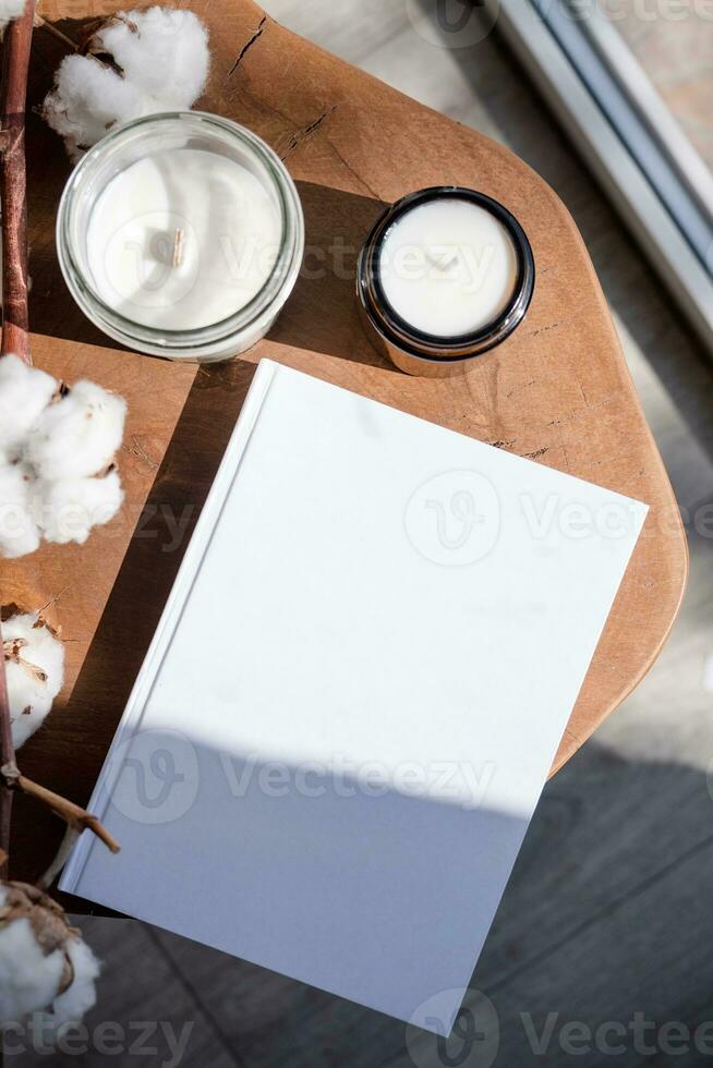 revista y libro Bosquejo diseño. blanco revista en moderno de madera mesa con velas , sombra cubrir foto