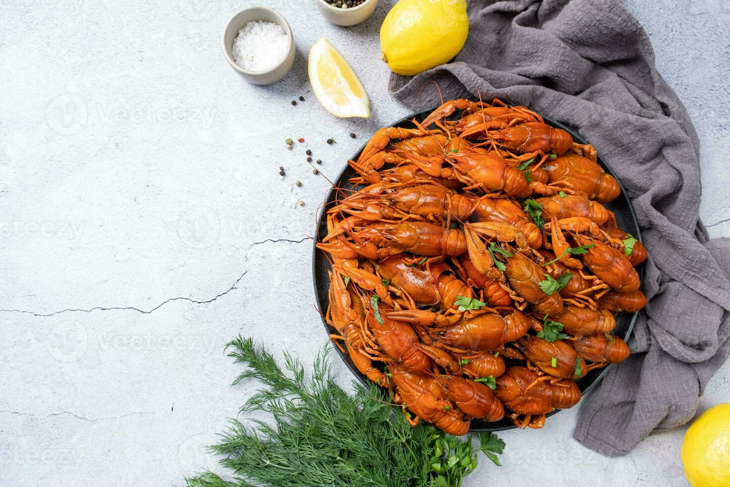 top view of cooked crawfish platter with lemons and spices on cement background photo