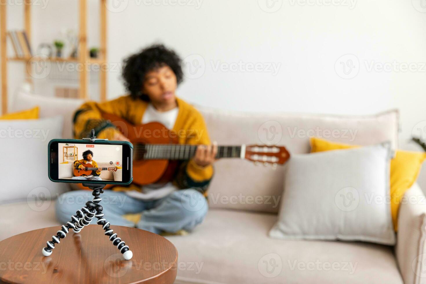 Blogger guitarist. African american girl blogger playing guitar talking to webcam recording vlog. Social media influencer woman streaming at home indoors. Music content creator broadcast tutorial. photo