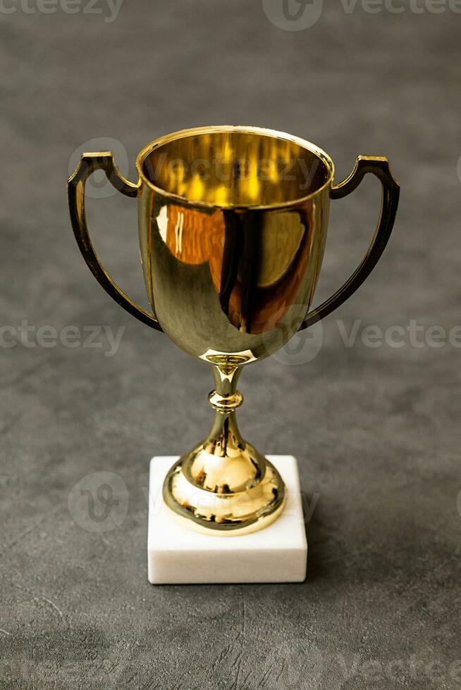 Simply design winner or champion gold trophy cup on concrete stone grey background. Victory first place of competition. Winning or success concept. Top view copy space. photo