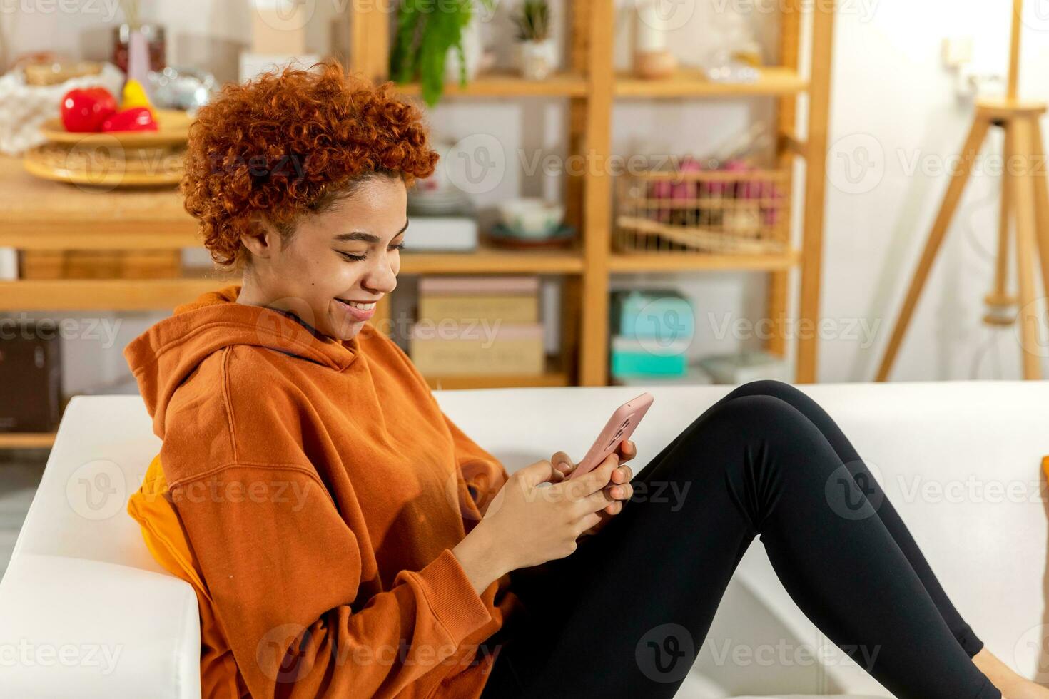 African girl holding smartphone touch screen typing scroll page at home. Woman with cell phone surfing internet using social media apps playing game. Shopping online Internet news cellphone addiction. photo