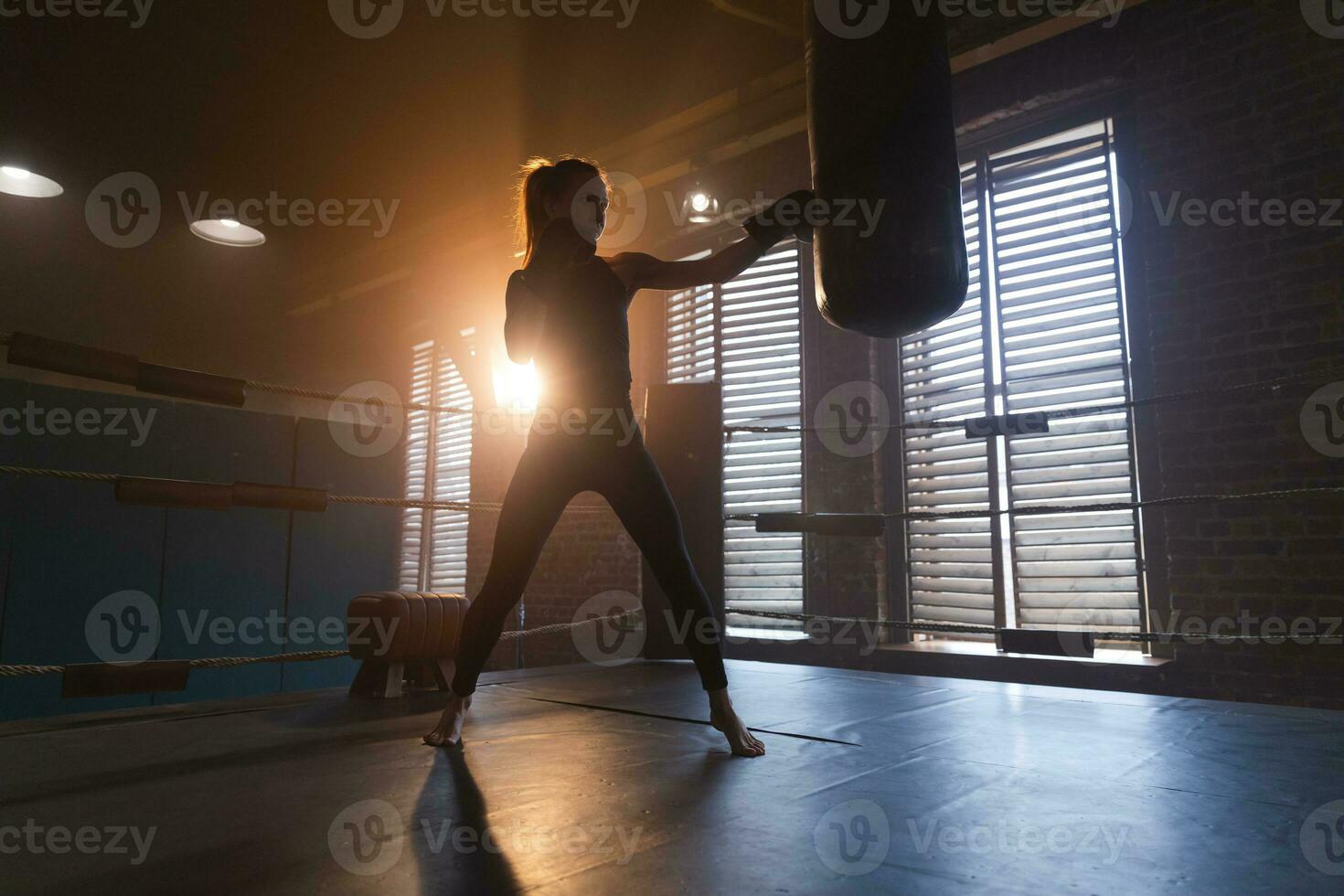 mujer yo defensa niña fuerza. fuerte mujer combatiente formación puñetazos en boxeo anillo. sano fuerte niña puñetazos boxeo bolsa. formación día en boxeo gimnasia. fuerza ajuste cuerpo rutina de ejercicio capacitación. foto