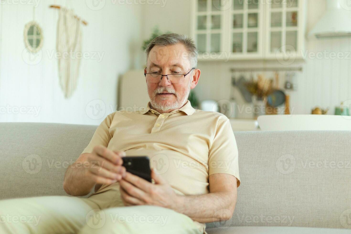 Happy middle aged senior man holding using smartphone touch screen typing scroll page. Stylish older mature beard grandfather with cell phone using internet social media apps at home. Shopping online. photo