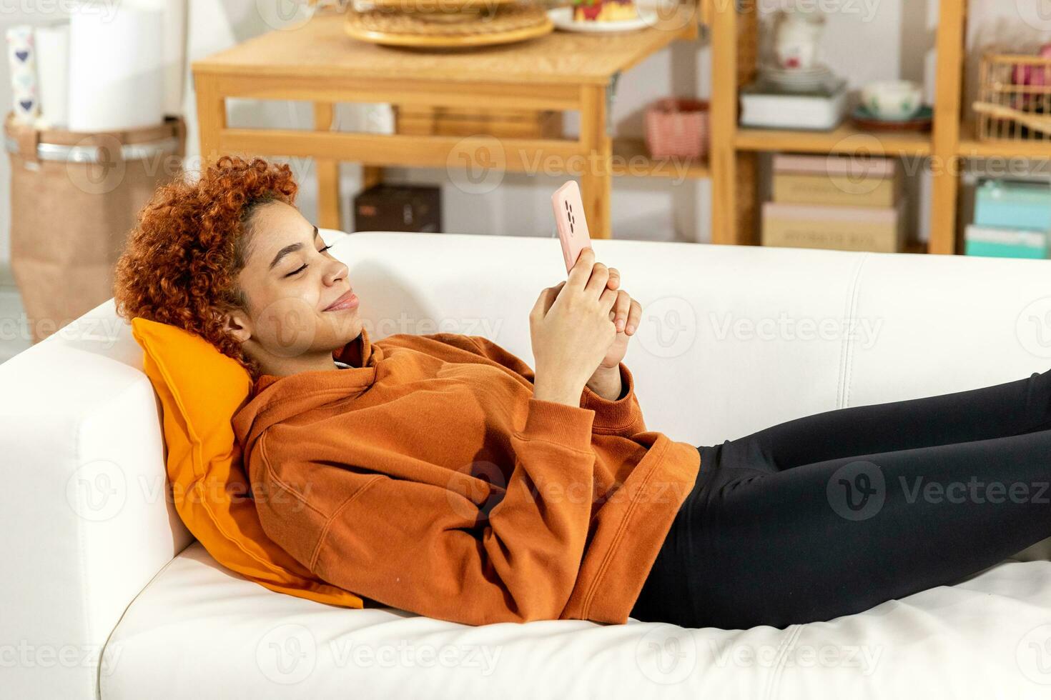 African girl holding smartphone touch screen typing scroll page at home. Woman with cell phone surfing internet using social media apps playing game. Shopping online Internet news cellphone addiction. photo