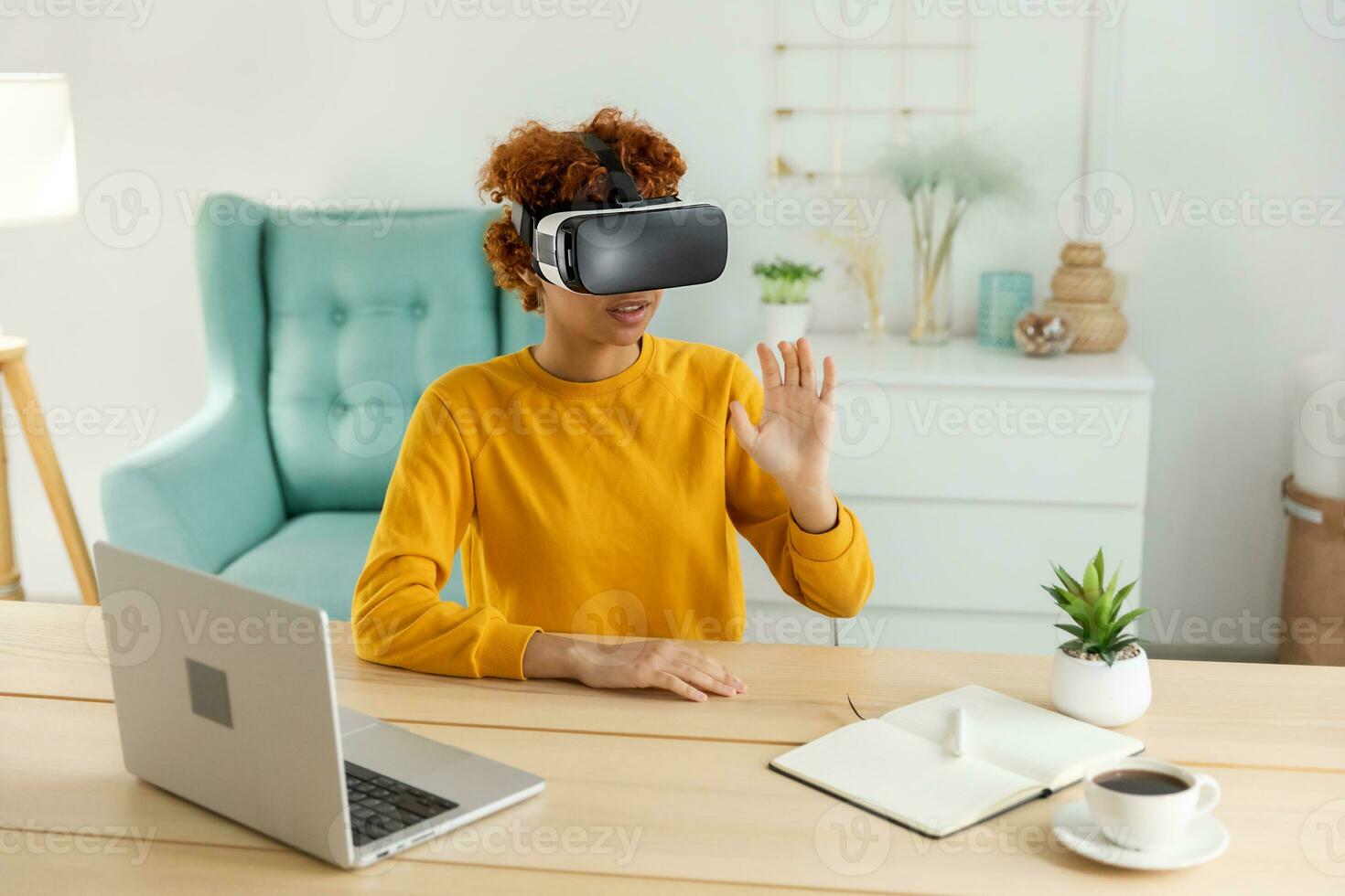 African american young woman wearing using virtual reality metaverse VR glasses headset at home. Girl touching air during VR experience on virtual reality helmet. Simulation hi-tech videogame concept. photo