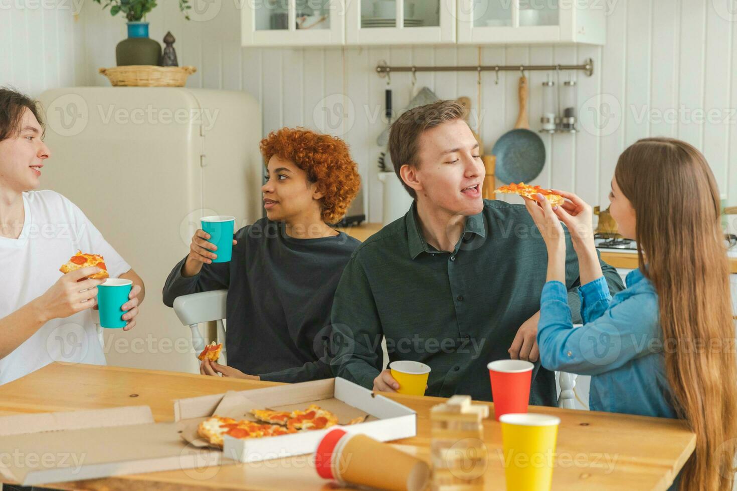 Home party Friends spending time together having fun laughing communicating at home. Happy diverse group eating pizza drinking beer or lemonade. Mixed race young buddies best friends enjoying weekend. photo